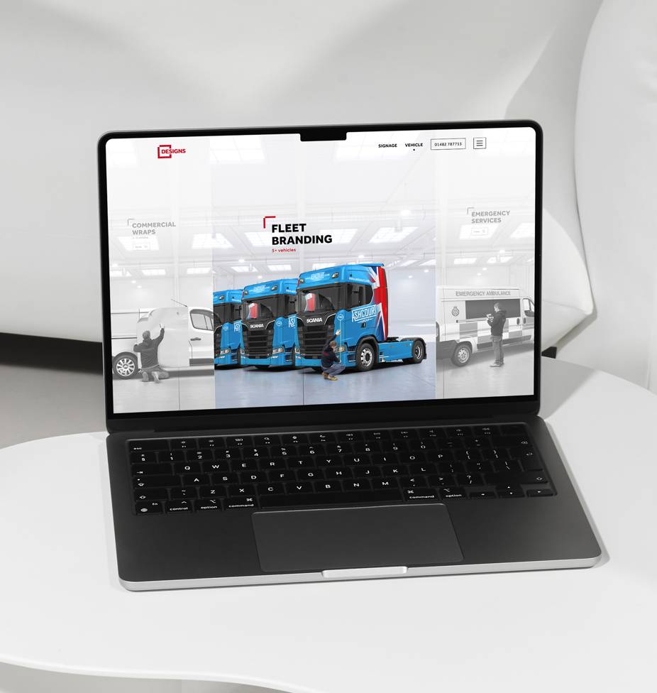 A laptop on a white table displays a website featuring fleet branding. It shows images of blue trucks and vehicles, with 'Fleet Branding' text.