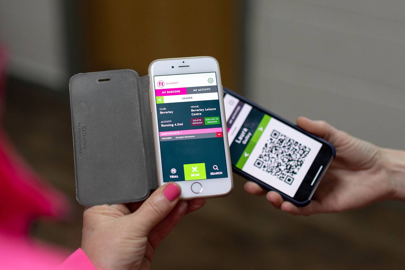 Two individuals holding smartphones. One phone displays a barcode scanning app interface, while the other shows a QR code.