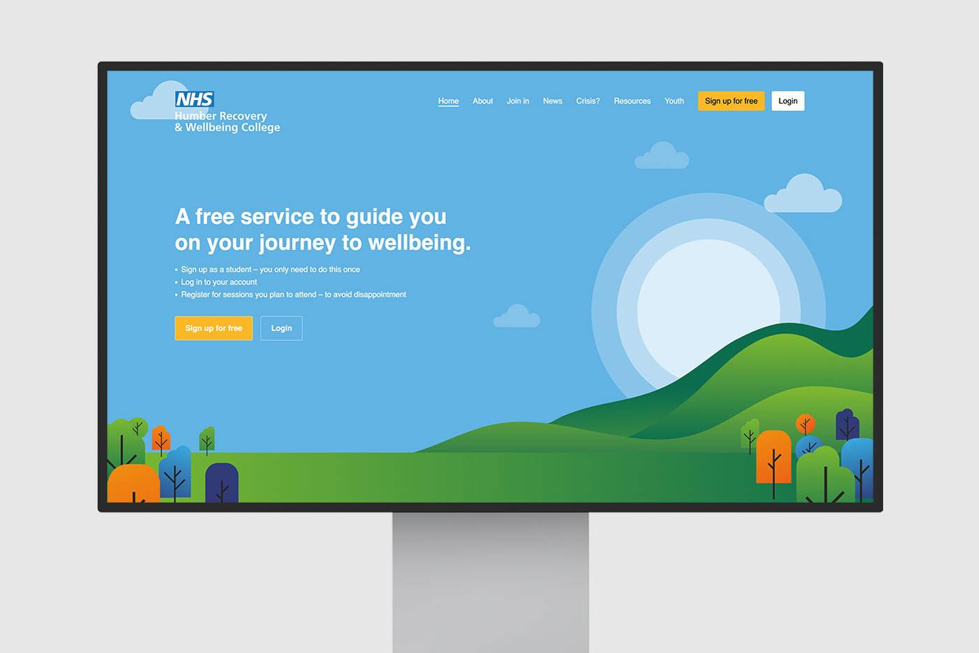 Monitor displaying the NHS Humber Recovery & Wellbeing College website. Features a blue sky, hills, and colourful trees.