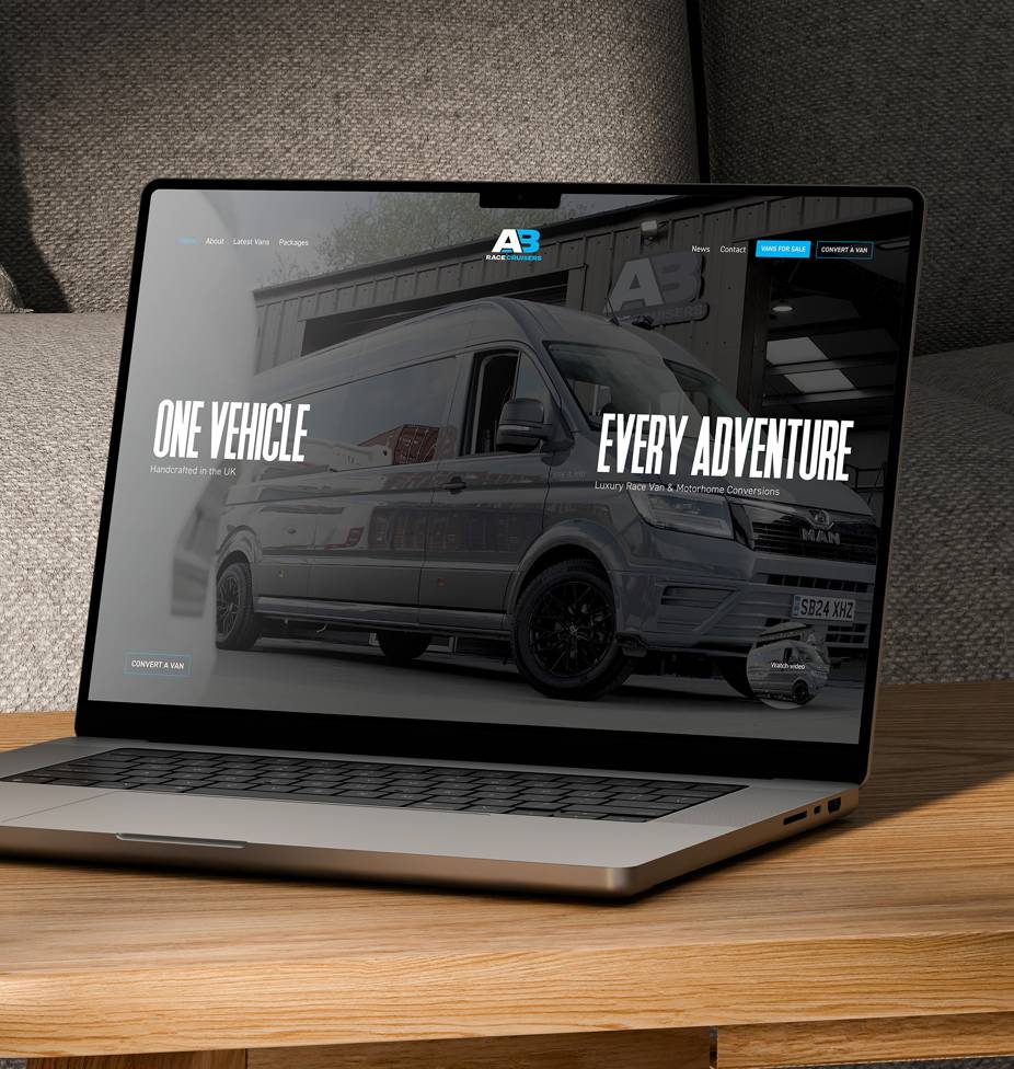 A laptop on a wooden table displaying the A3 Race Vans website