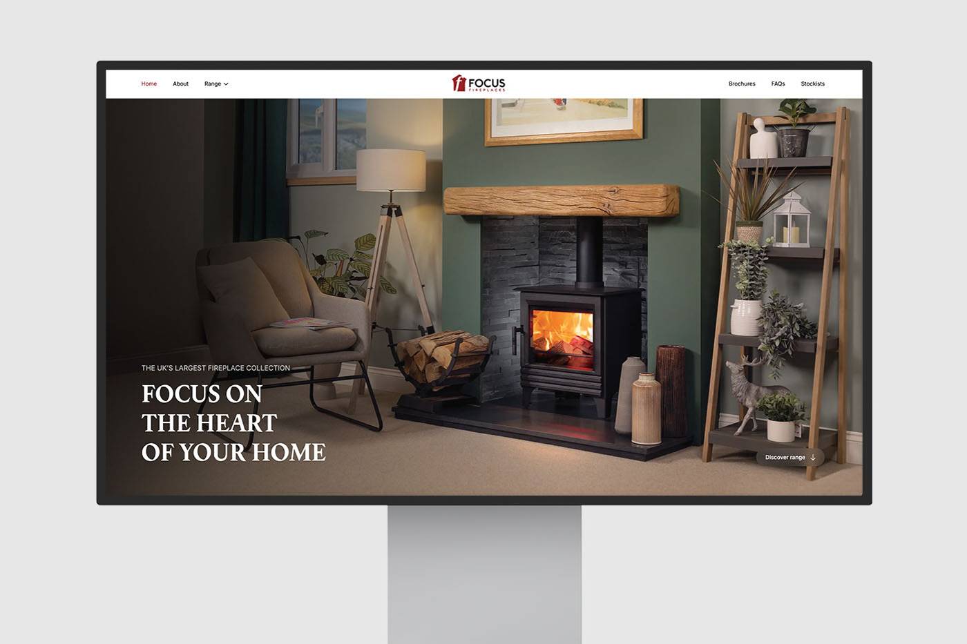 A computer monitor displays a cozy living room scene with a lit fireplace, armchair, and stylish shelves. The screen text reads 'Focus on the Heart of Your Home.'
